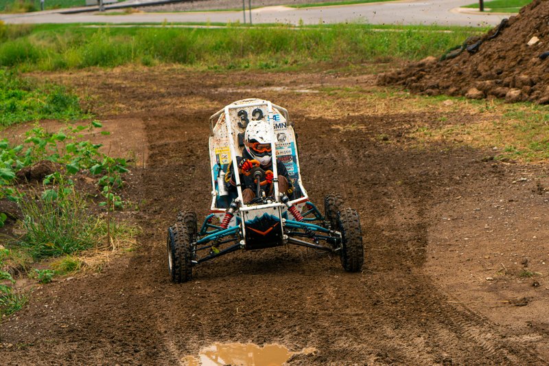 Baja car number 32 driving toward the camera along a muddy rutted track