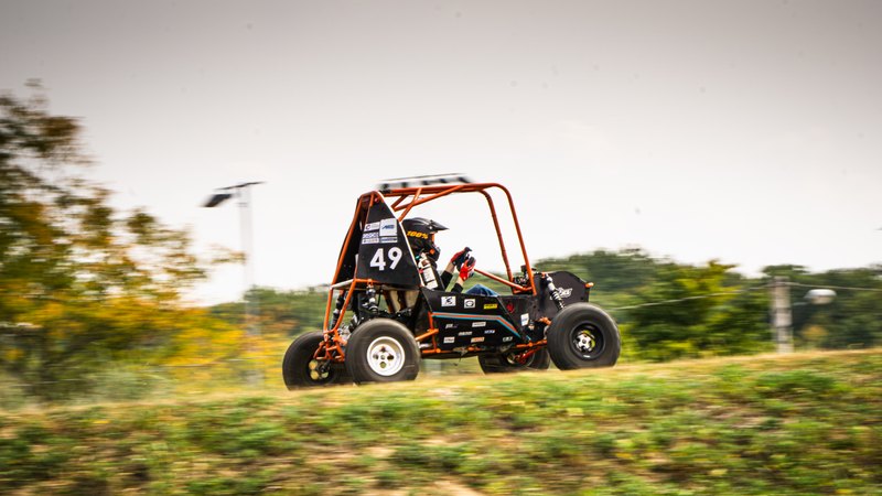 Orange ONU Baja SAE car number 49 testing on a dirt and gravel course