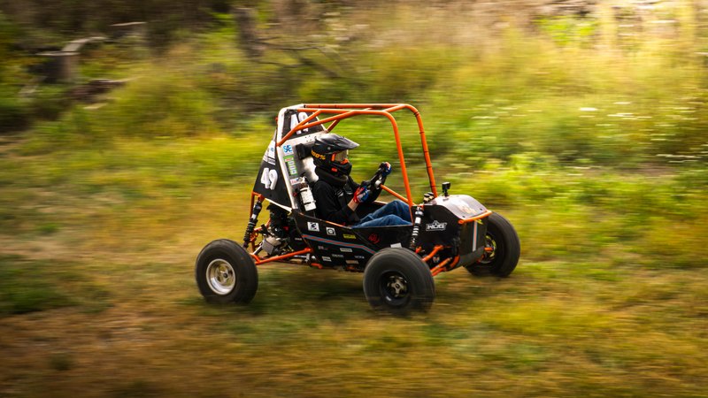 Orange ONU Baja SAE car number 49 testing on a dirt and gravel course
