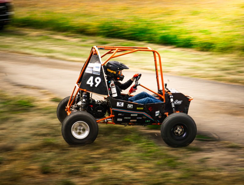 Side panning shot of Baja car number 49 with the track running diagonally