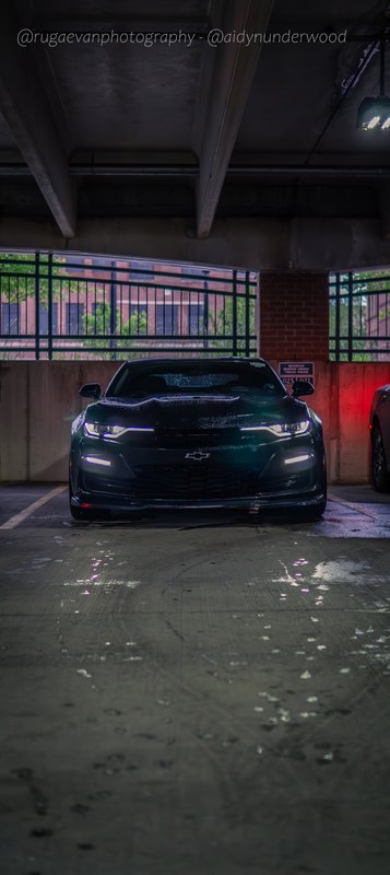 Dark muscle car in a concrete parking garage at night