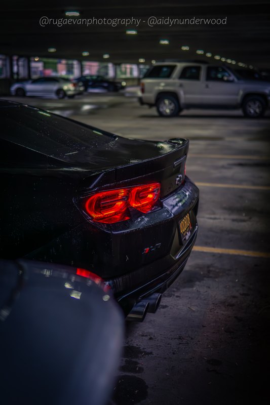 Dark muscle car in a concrete parking garage at night