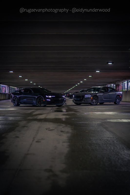 Dark muscle car in a concrete parking garage at night