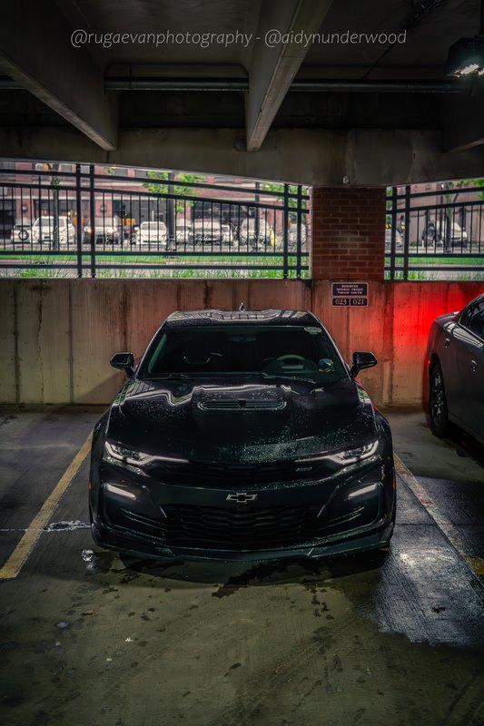 Dark muscle car in a concrete parking garage, low angle
